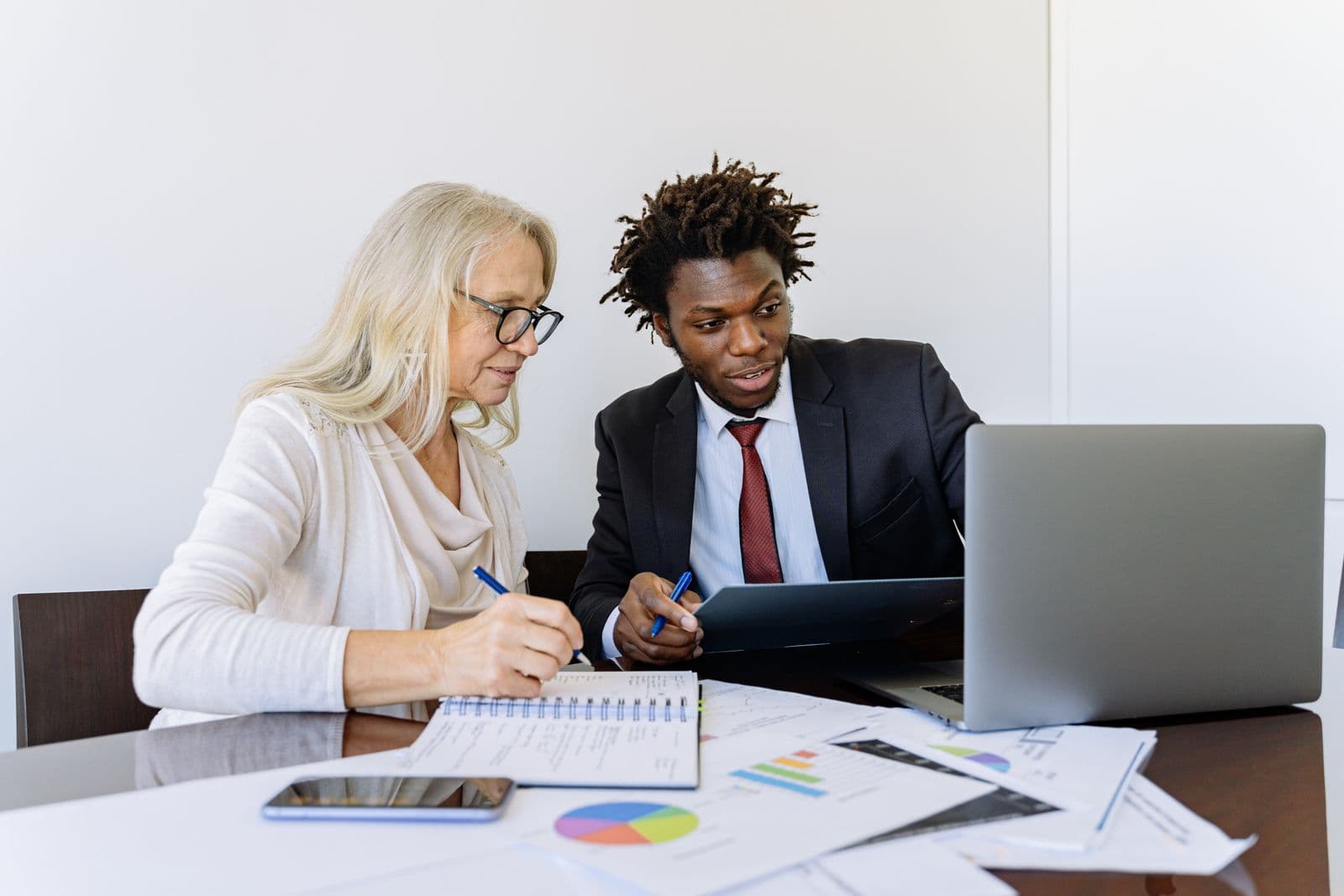 Two advisers reviewing student applications and reports together at a desk