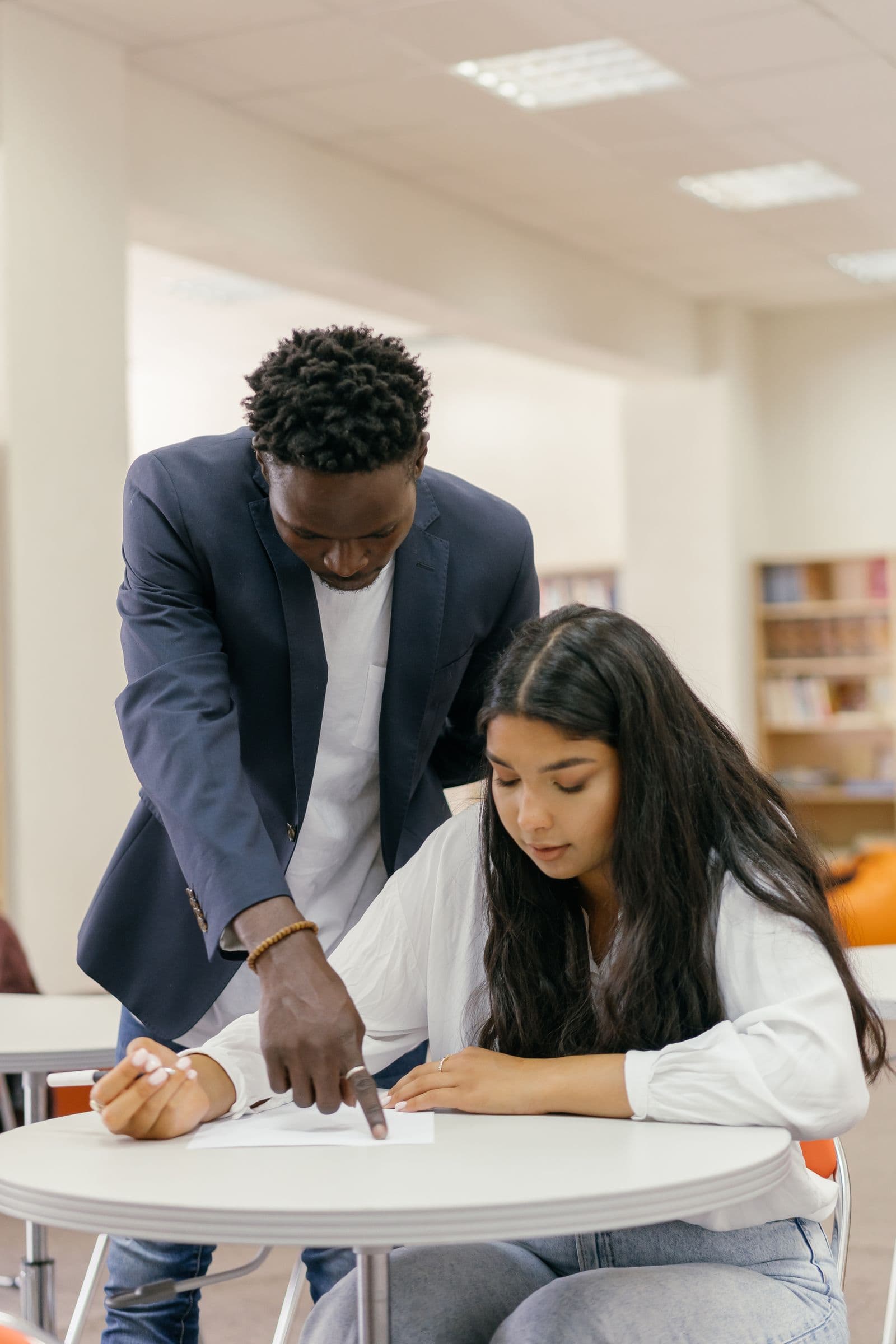 A counsellor guiding a student through paperwork at a study table